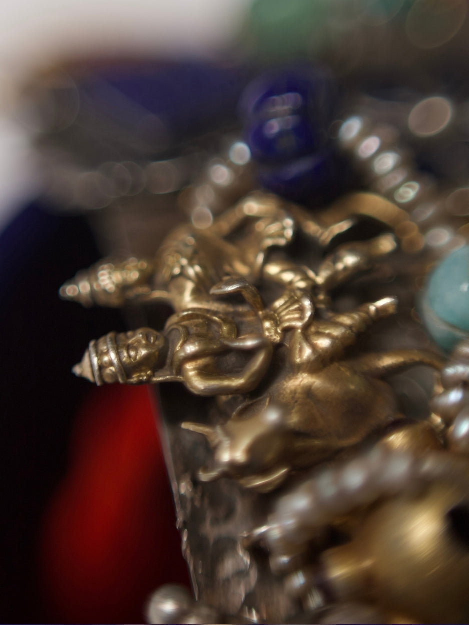 Close-up of a handcrafted 92.5 silver choker with temple and goddess motifs, red and green stonework, gold accents, and layered pearl strands.