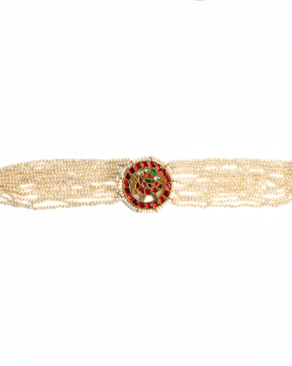 Close-up of a layered pearl choker in 925 silver with gold polish featuring a circular red stone peacock medallion at the centre.