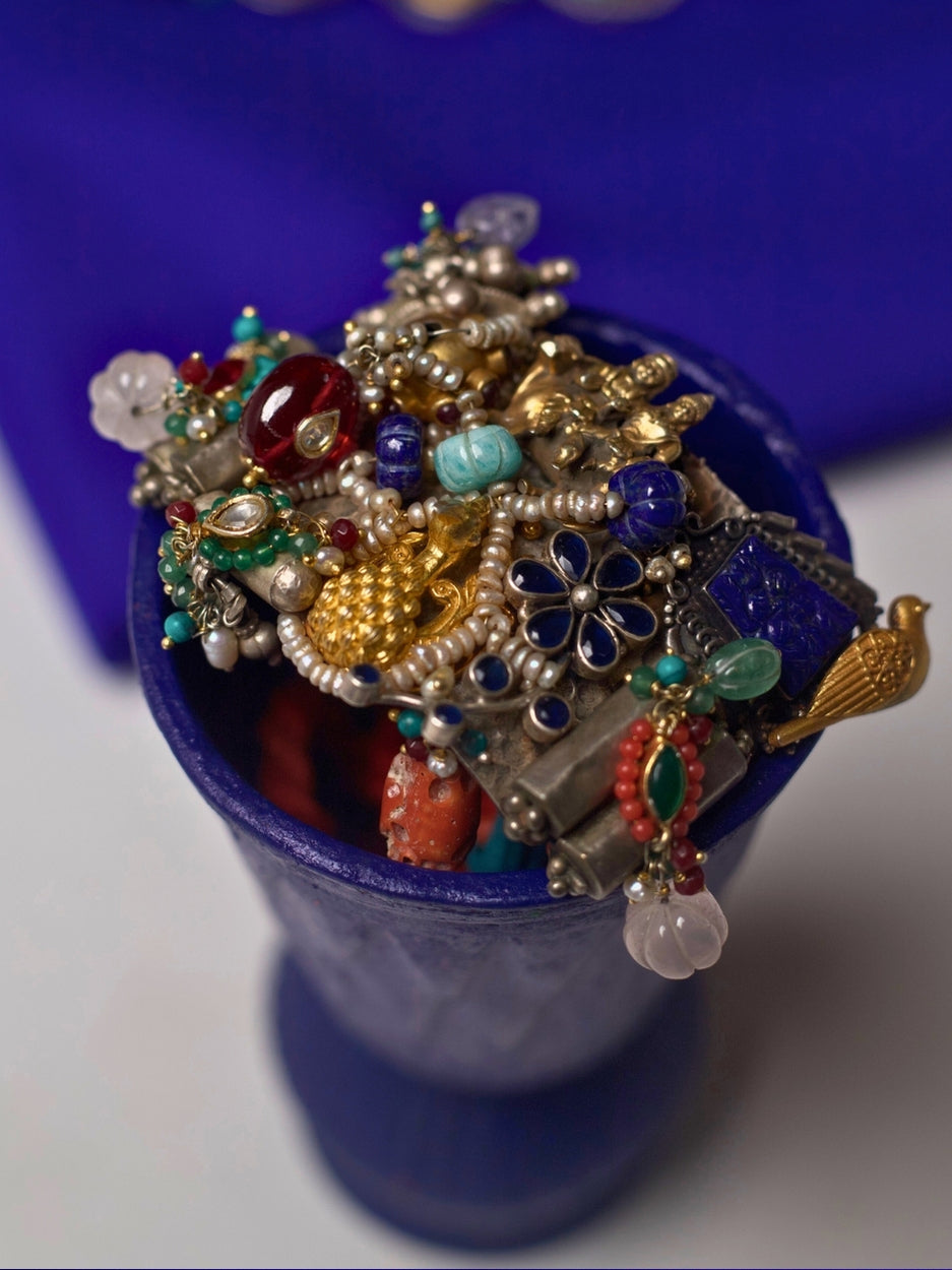 Close-up of a handcrafted 92.5 silver choker with temple and goddess motifs, red and green stonework, gold accents, and layered pearl strands.