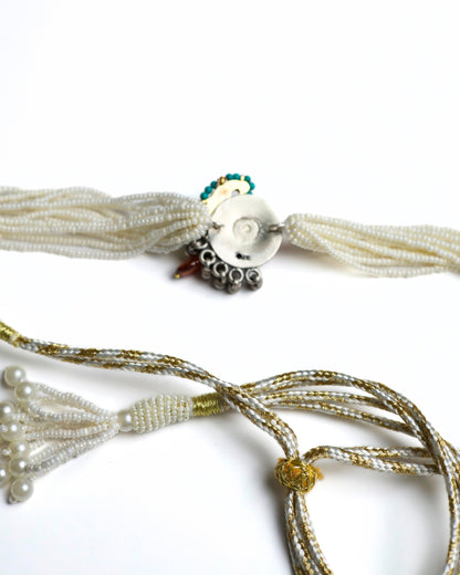 Multi-strand pearl choker with turquoise circular centre, teardrop kundan stone, red bead halo and green stone accents in 925 silver with gold polish.
