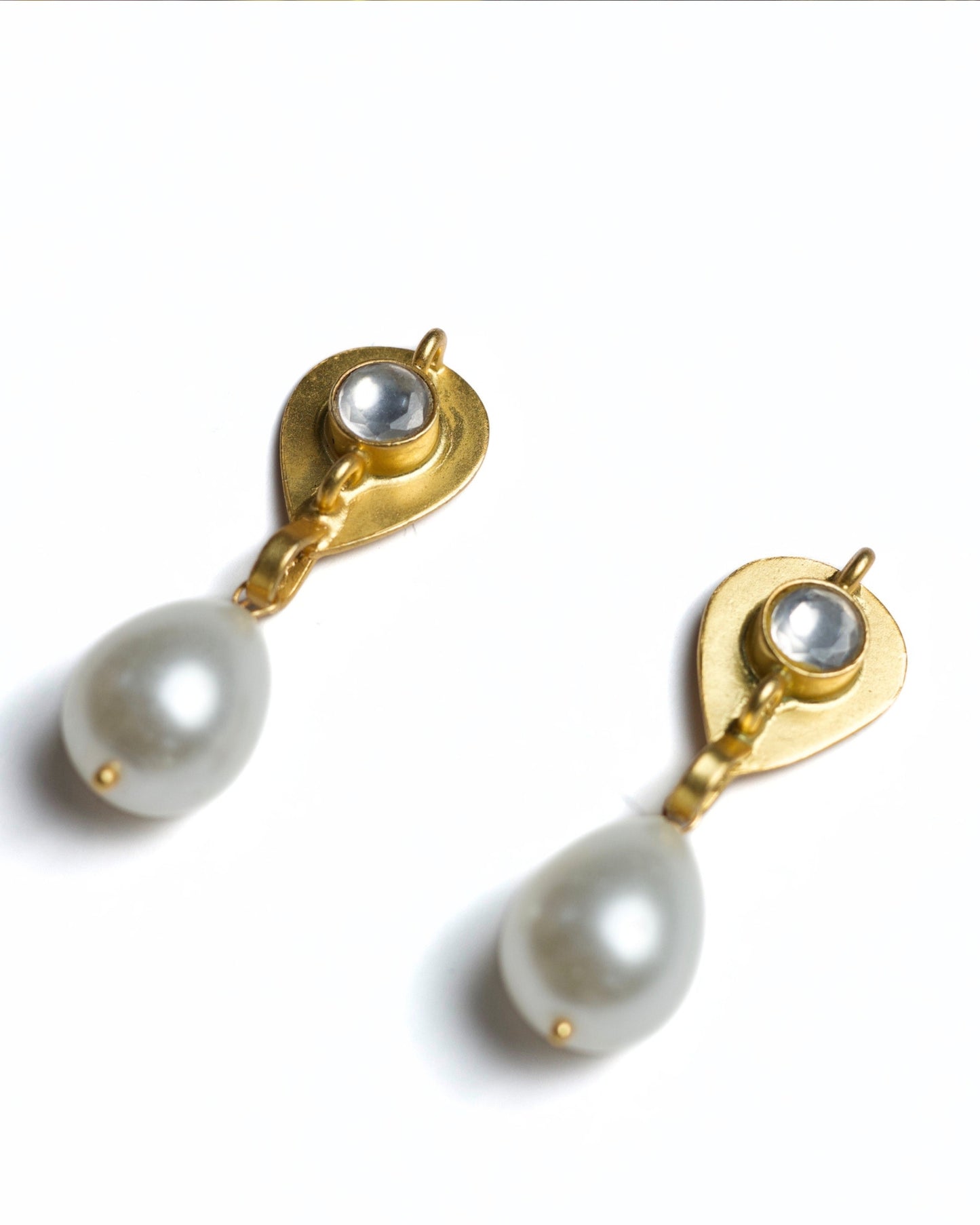 Close-up of gold-polished 925 silver drop earrings featuring a faceted clear stone stud and a suspended white teardrop pearl.