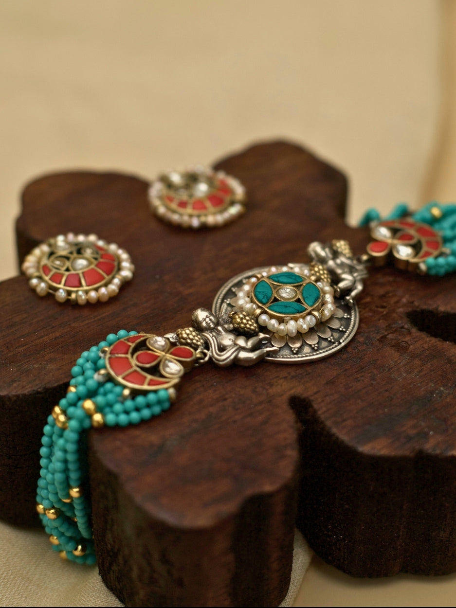 Saffron Skies Choker Set in pure 925 silver with layered firozi stones, orange tikras, angel motifs, and pearl drop earrings by Naksa.