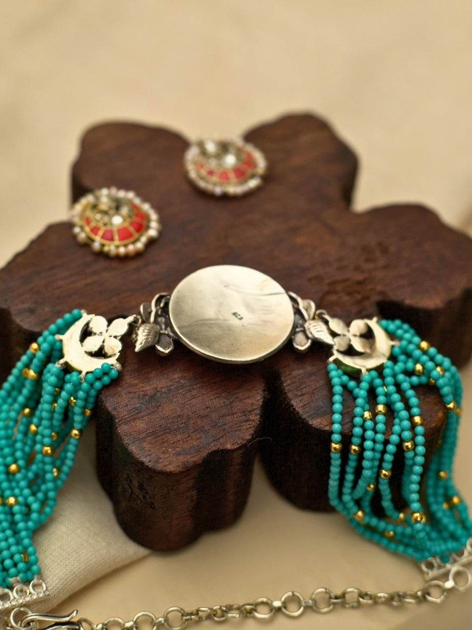 Saffron Skies Choker Set in pure 925 silver with layered firozi stones, orange tikras, angel motifs, and pearl drop earrings by Naksa.