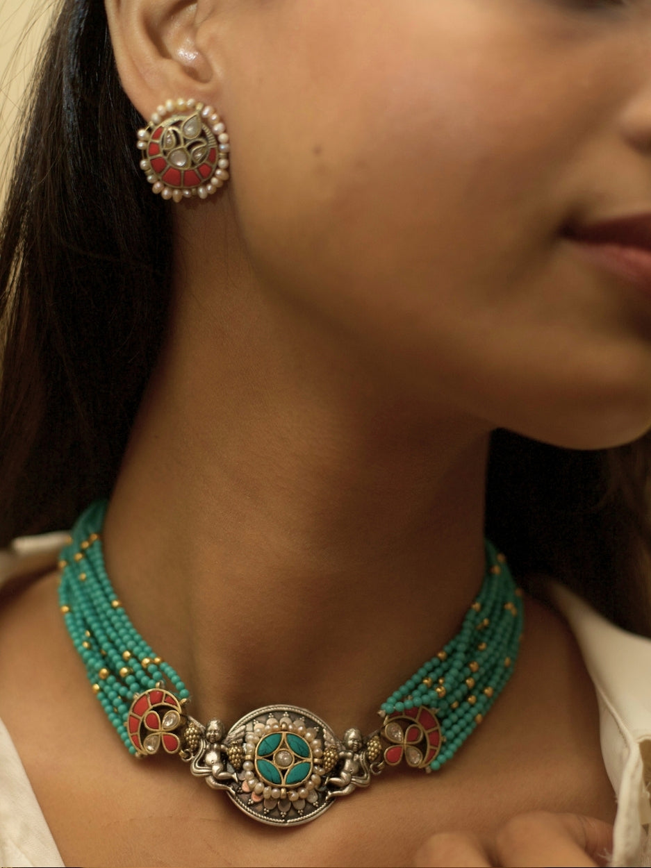 Saffron Skies Choker Set in pure 925 silver with layered firozi stones, orange tikras, angel motifs, and pearl drop earrings by Naksa.