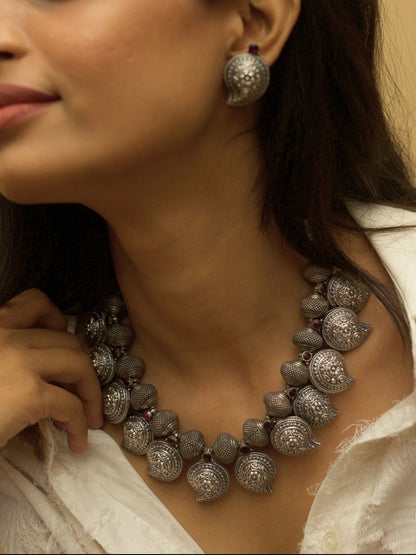 Temple Ambi Set by Naksa—oxidized 925 silver necklace and stud earrings with paisley motifs and wine-red accents.