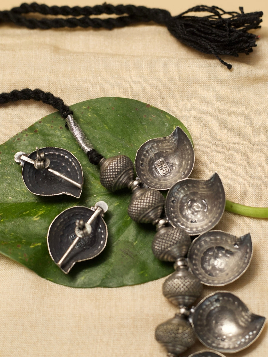 Temple Ambi Set by Naksa—oxidized 925 silver necklace and stud earrings with paisley motifs and wine-red accents.
