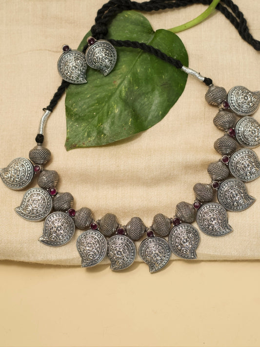 Temple Ambi Set by Naksa—oxidized 925 silver necklace and stud earrings with paisley motifs and wine-red accents.