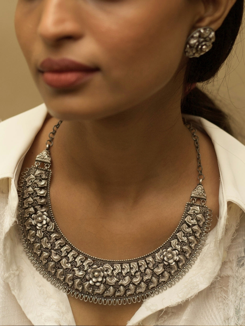 Jalrupi Haar by Naksa—oxidized 925 silver crescent necklace with fish and floral motifs, paired with round floral stud earrings.