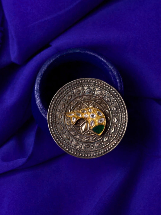 92.5 silver engraved medallion ring featuring gold kundan fish motif with green enamel on deep blue cloth backdrop.