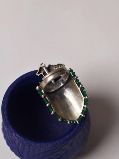 Close-up of handcrafted 92.5 silver ring with sculpted gold-tone bull, temple etching, red enamel leafwork, and green stone detail – Naksa Jewelry