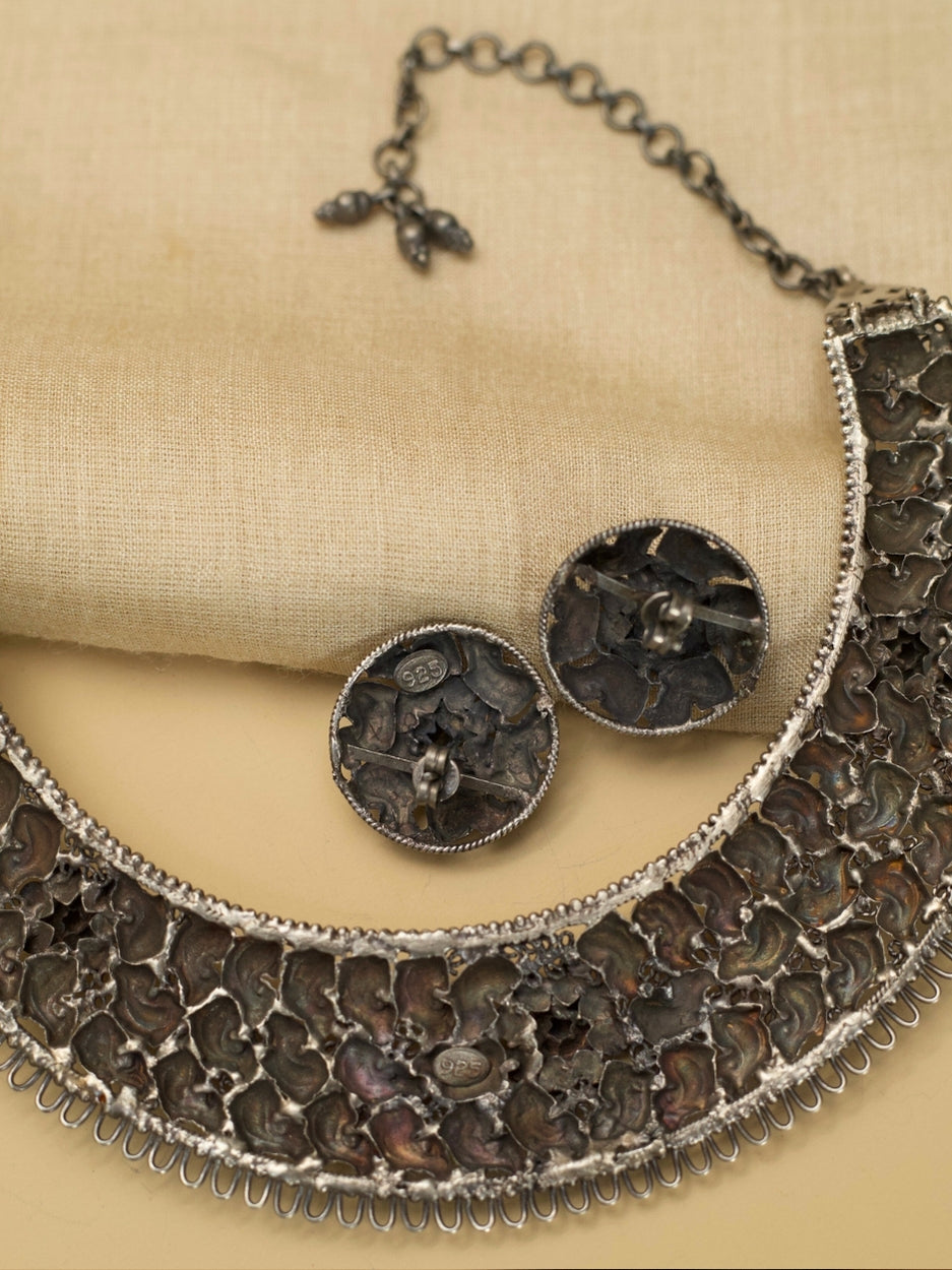 Jalrupi Haar by Naksa—oxidized 925 silver crescent necklace with fish and floral motifs, paired with round floral stud earrings.
