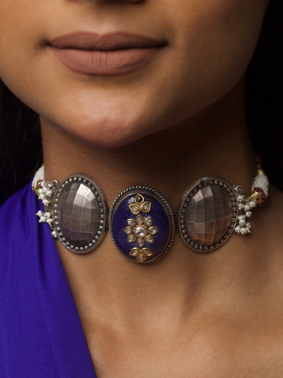 Close-up of Nightfall Empress Choker in pure 92.5 silver featuring a lapis centre with kundan and two faceted silver domes, styled on model's neck.