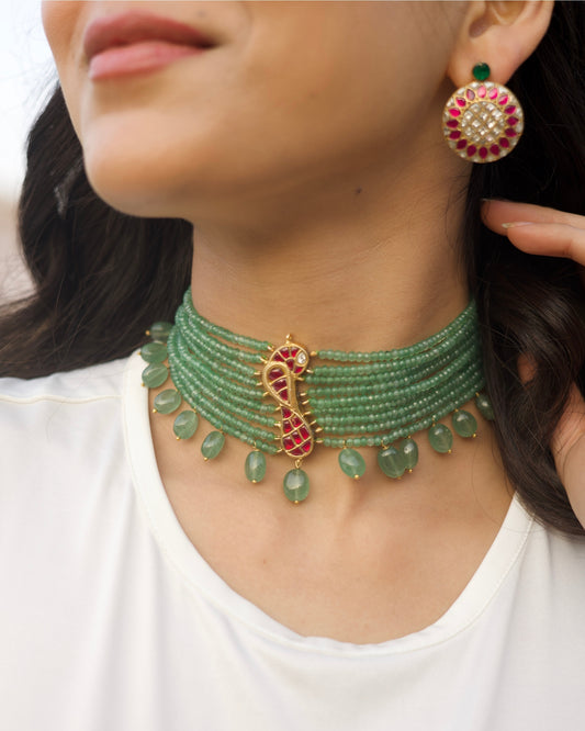 Green multi-strand beaded 925 silver choker with gold polish, red kundan-style bird motif at centre, and dangling green stone drops along the base.
