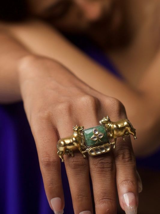 Close-up of handcrafted Dharohar Ring in pure 92.5 silver featuring twin golden cow motifs, kundan inlay, and green stone centerpiece