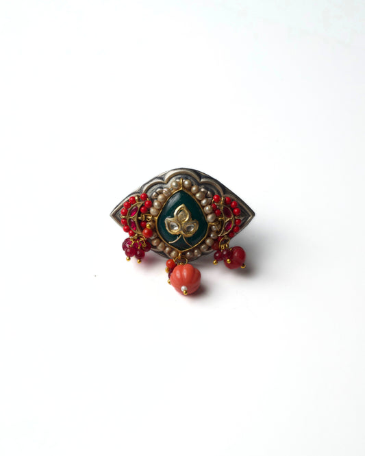 The Sacred Eye Ring in 925 silver featuring an almond-shaped design with green centre stone, pearl border, and red bead detailing