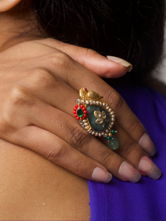 Close-up of The Sparrow’s Secret Ring in 92.5 silver with gold-toned sparrow, pearls, green stone, and drop bead detailing