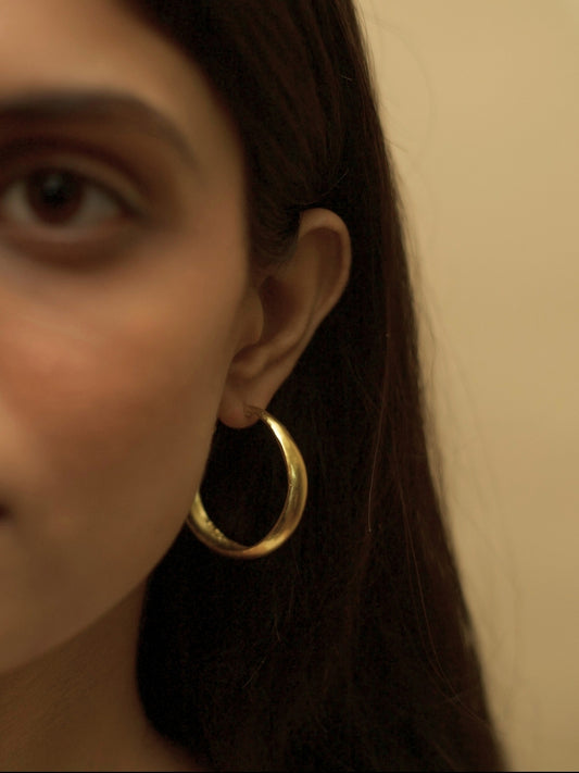 Hoops for Good earrings by Naksa—pure 925 silver gold small hoop earrings with smooth finish, shown worn on ear.