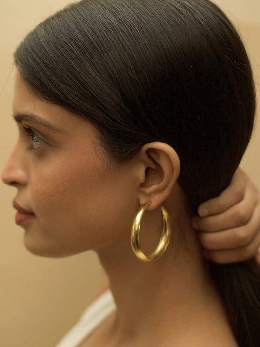 Hoops for Good earrings by Naksa—pure 925 silver gold classic hoop earrings with smooth finish, shown worn on ear.