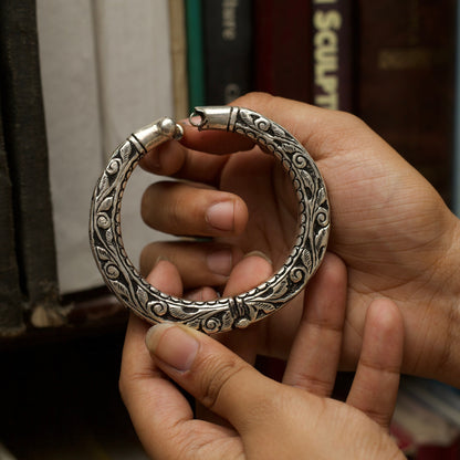 With winding vines nodding to the wisdom flowing through millenniums and the rustic dark finish of oxidised silver, this handcrafted engraved silver bangle comes with an adjustable toggle clasp. This bangle fits perfectly on your wrists and is durable and lightweight.
