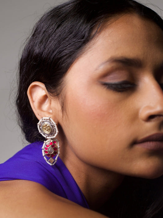 Close-up of The Petal Pact Earrings featuring a 92.5 silver base, golden floral motif with pearls on top, and a bold pink-stone drop element—styled on ear.