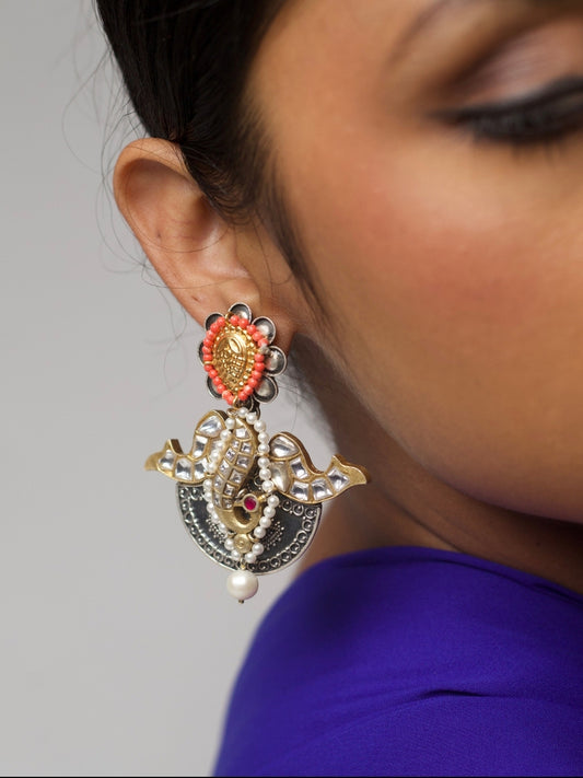 Close-up of The Winged Teardrop Earrings by Naksa—featuring 92.5 silver, kundan stone setting, peacock motif, coral beading, and pearl details, worn on ear