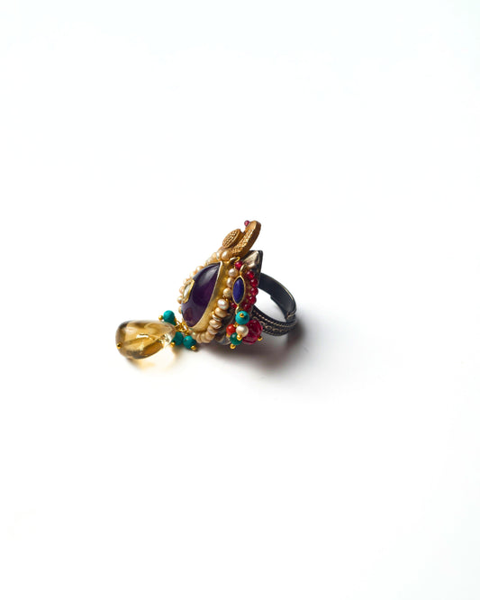 Side view of the Indigo Perch Ring in 925 silver showing the raised parrot motif, vertical structure, pearl detailing, and suspended accent stones.