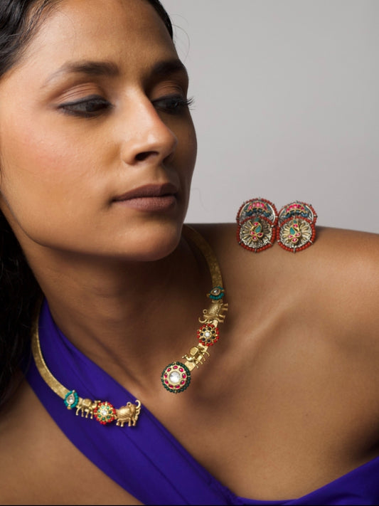 Close-up of The Tusker March Set – handcrafted 92.5 silver torque necklace with gold-plated elephant motifs and enamel detailing in red and green, styled with matching earrings.