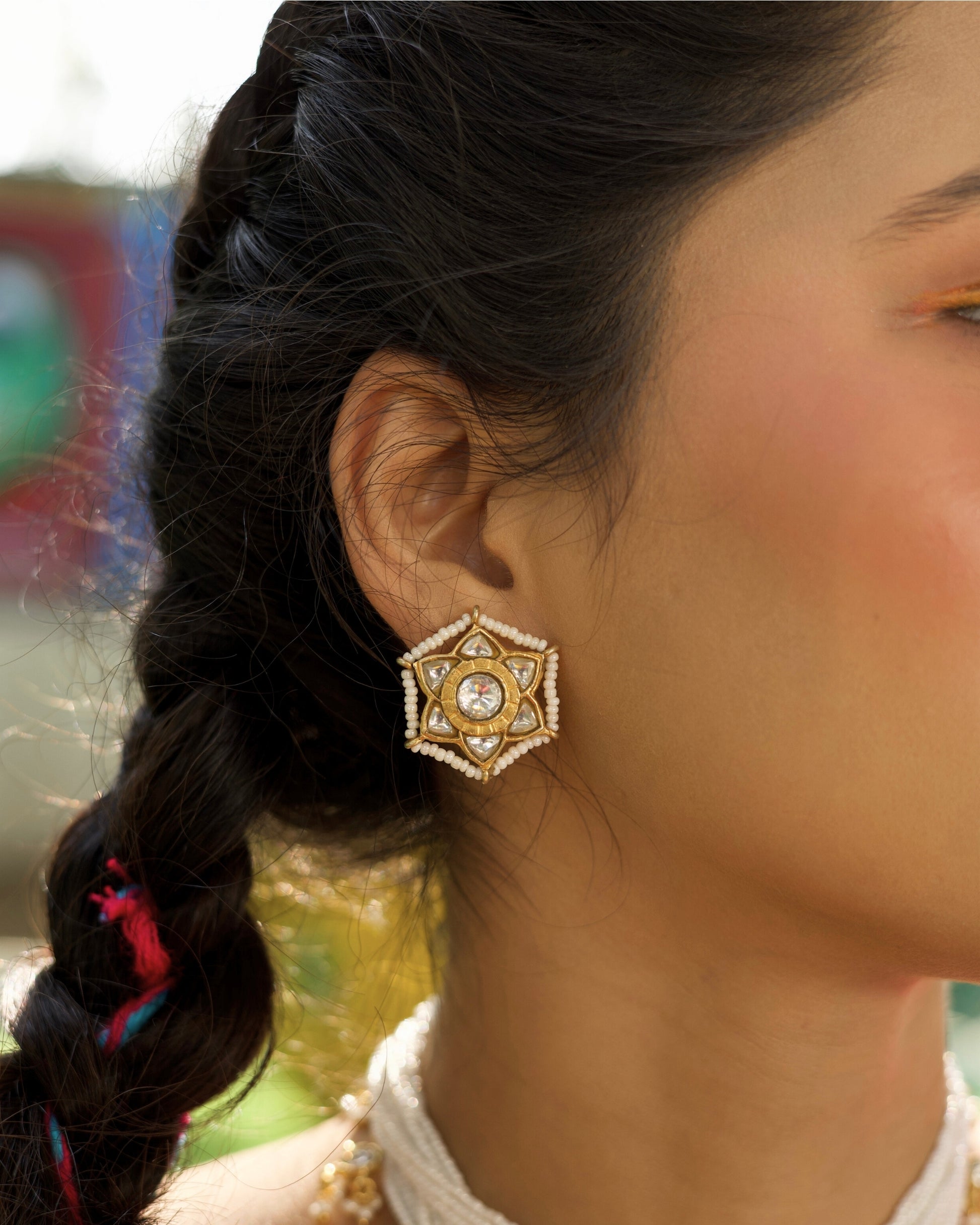 Star-shaped silver stud earrings with white stones and gold polish