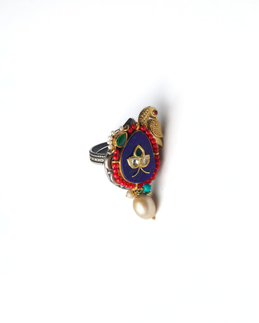 Front view of The Violet Parrot Ring in 925 silver, featuring a violet enamel centre, sculpted parrot motif, red beaded edging, and pearl drop detailing