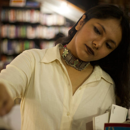 This oxidised 92.5 silver choker features three meticulously designed fish cutouts in lush pastel green, with scarlet and white gemstones on an embossed base flanked by ghunghroo beads. It comes with a shiny pink, adjustable dhaaga that perfectly complements the colours and adds a vintage charm.