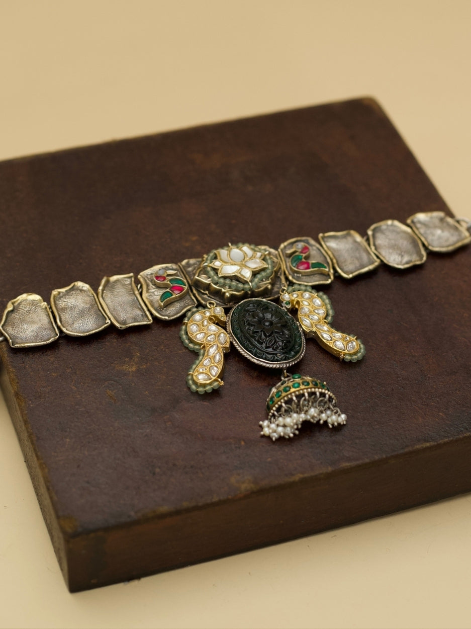 Close-up of Naksa's handcrafted Peacock Mirage Choker in 92.5 silver featuring lotus centrepiece, carved green stone, and kundan-set bird.