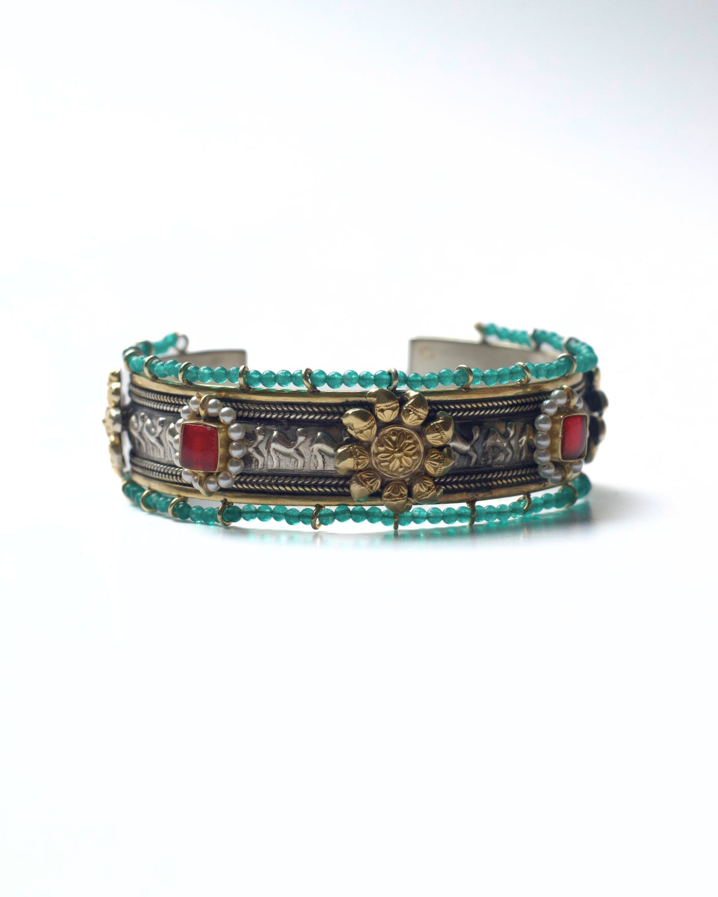 Front view of The Floral Desert Bangle in 925 silver featuring a central floral motif, sculpted relief detailing, turquoise bead borders, and red stone accents