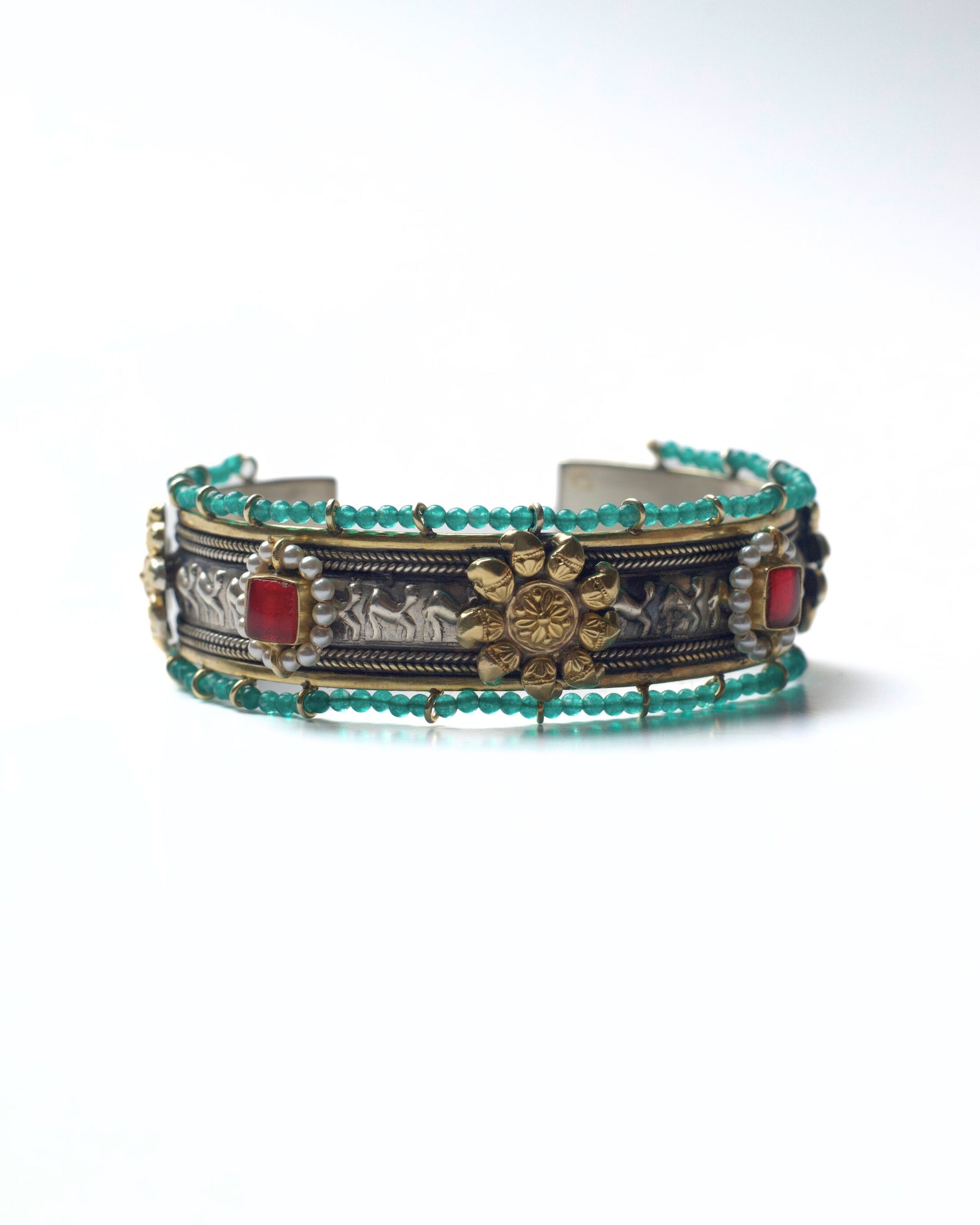 Front view of The Floral Desert Bangle in 925 silver featuring a central floral motif, sculpted relief detailing, turquoise bead borders, and red stone accents