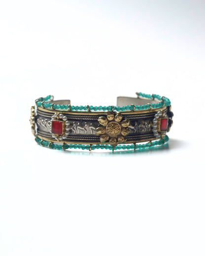 Front view of The Floral Desert Bangle in 925 silver featuring a central floral motif, sculpted relief detailing, turquoise bead borders, and red stone accents
