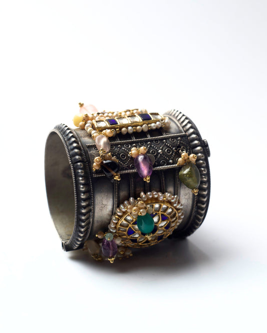 Wide oxidised 925 silver cuff featuring circular kundan medallions in deep blue and ivory, framed with pearls and gold-toned detailing.