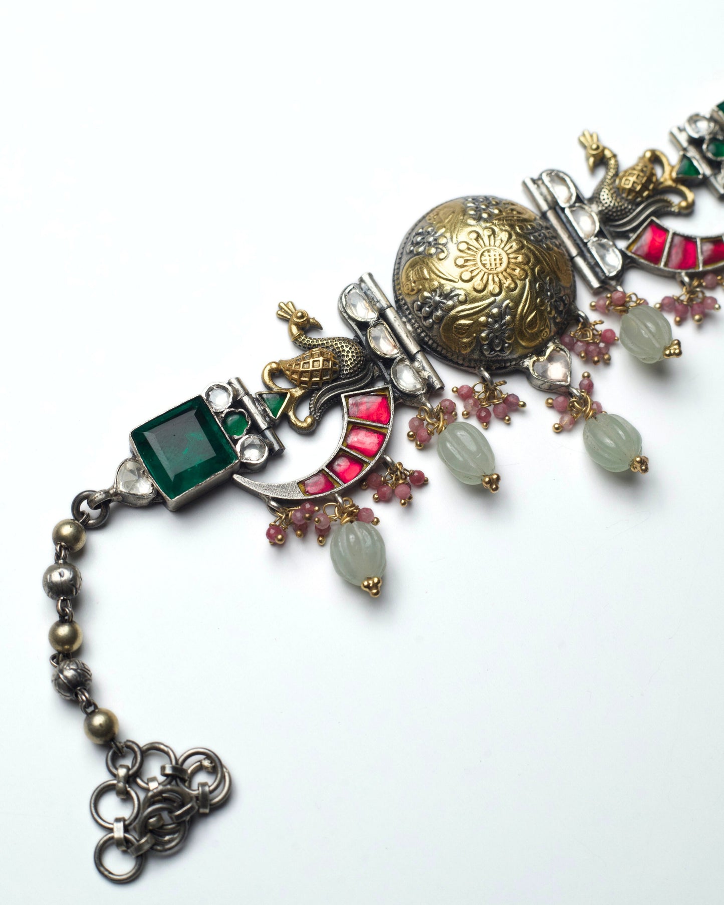 Side detailing of sculpted peacock motifs with gold accents and green stones on The Peacock Halo Choker.