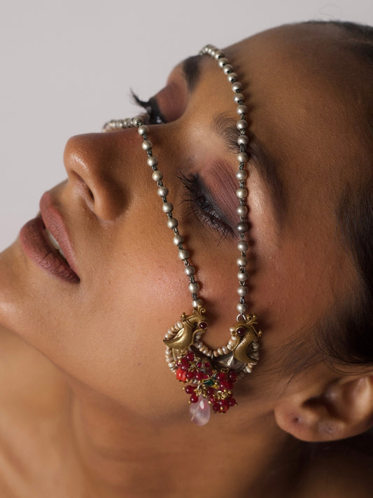 92.5 silver necklace featuring two golden parrot motifs with carved silver base, pink gemstone drop, and pearl-beaded chain, designed by Naksa
