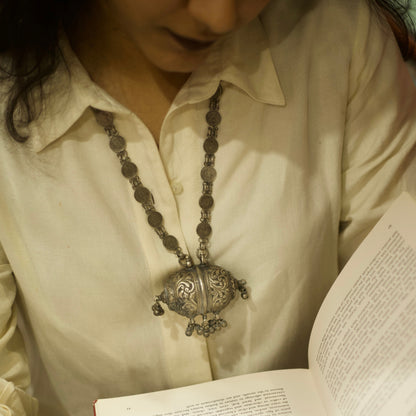 This antique silver necklace features a cylindrical box-shaped pendant with detailed engravings and&nbsp;ghunghroo beads. The chain has circles carved with the portraits of royal queens. This 925 oxidised silver necklace is a regal piece of contemporary jewellery that'll be cherished as a heirloom for years to come!&nbsp;