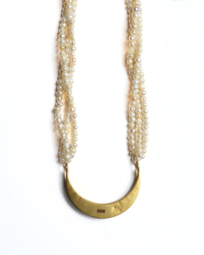 Close-up of pearl necklace with gold-toned crescent centre