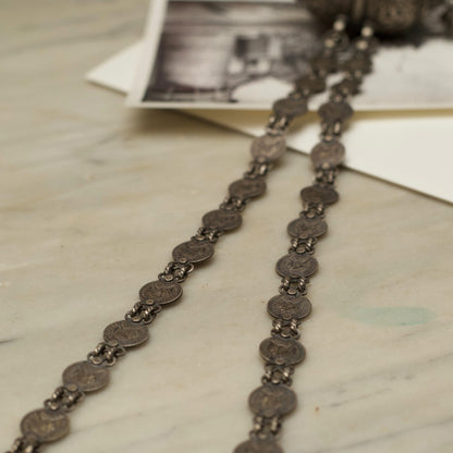 This antique silver necklace features a cylindrical box-shaped pendant with detailed engravings and&nbsp;ghunghroo beads. The chain has circles carved with the portraits of royal queens. This 925 oxidised silver necklace is a regal piece of contemporary jewellery that'll be cherished as a heirloom for years to come!&nbsp;