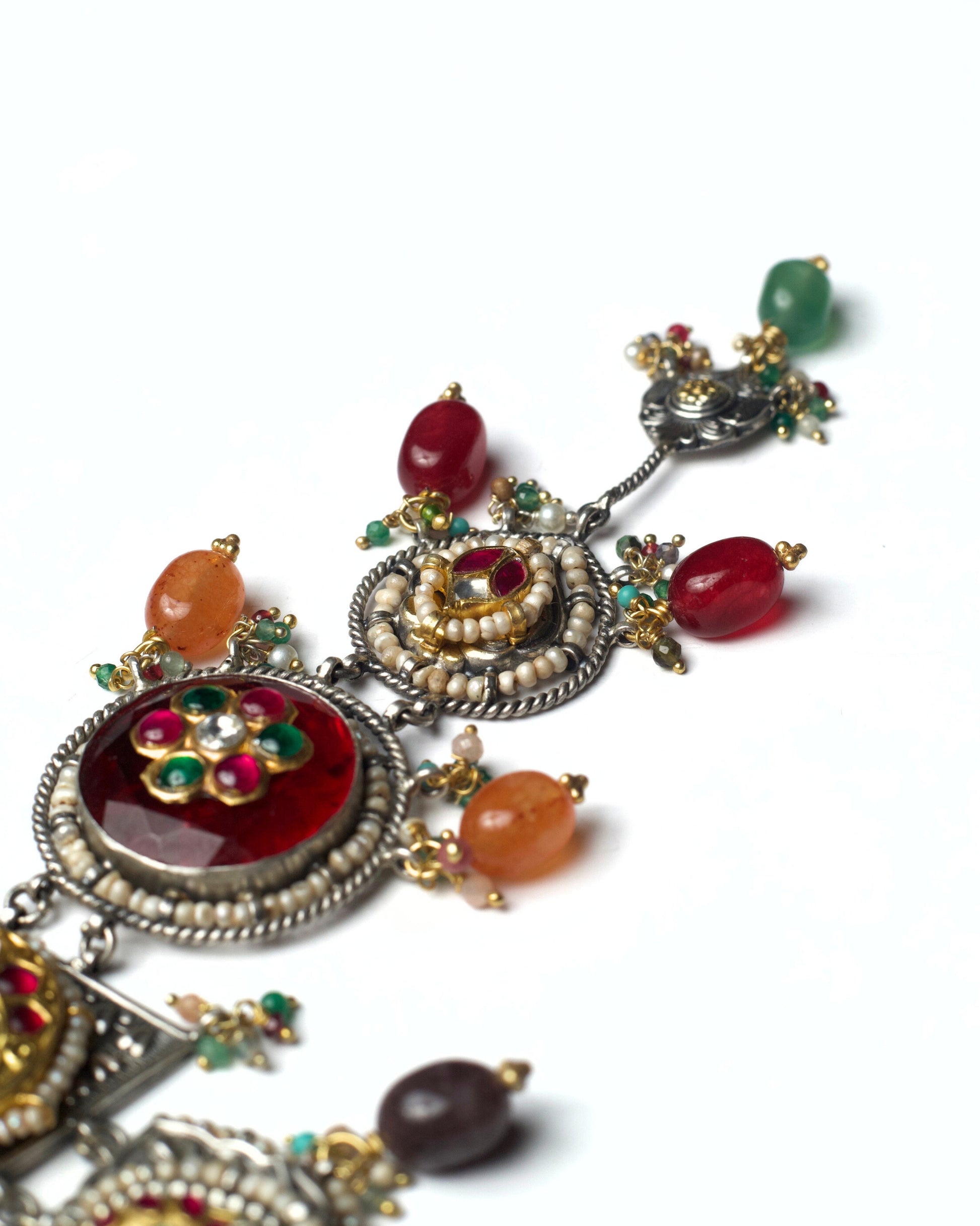 Red, amber, and green stone drops suspended from a layered oxidised silver heirloom necklace