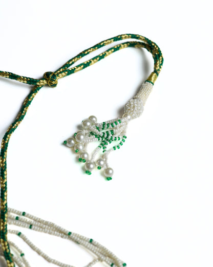 Multi-strand pearl necklace with emerald bead highlights and crescent pendant