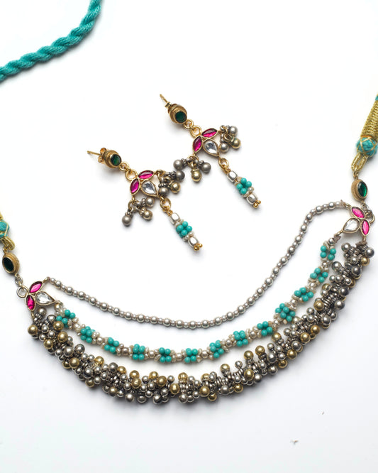 Handcrafted silver necklace with layered ghungroo detailing, turquoise bead clusters, silver pearls, and kundan accents arranged in a fluid, textured design.