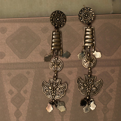 These dangling tiered earrings resemble an enchanting ladder out of a fairytale reaching for the moon. This fusion silver jewellery piece s intricately embossed with nature-inspired motifs and is lightweight and durable.