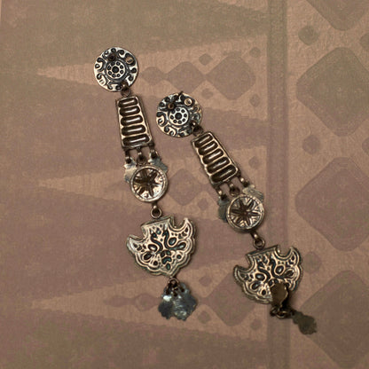 These dangling tiered earrings resemble an enchanting ladder out of a fairytale reaching for the moon. This fusion silver jewellery piece s intricately embossed with nature-inspired motifs and is lightweight and durable.