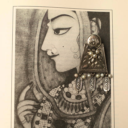 These oxidised silver earrings are a tribute to the ageless charm of Indian women told through great classic and contemporary stories. They feature a round stud engraved with the lotus, an asymmetric shape with dangling elements and thoughtful pearl work that make it hard to miss.