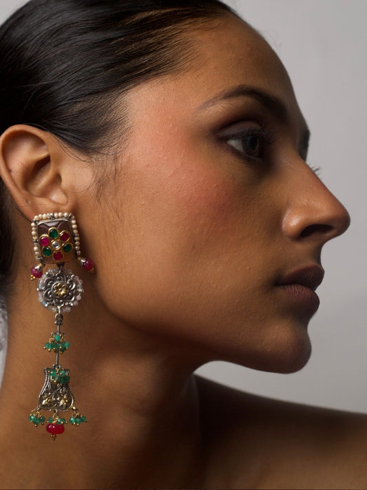 Close-up of a woman wearing Pretty Peculiar Earrings in pure 92.5 silver, featuring layered design with pearl-framed red and green enamel stud, oxidised silver floral centre, and dangling ornate drop with green and pink beads.