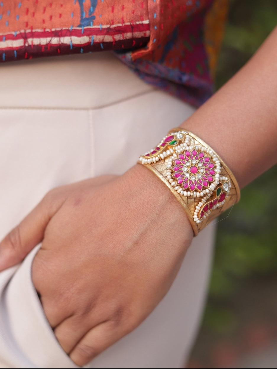 Woman wearing Naksa’s Sunkissed Rose Cuff in gold-finished silver, featuring a pink stoneflower with pearl.