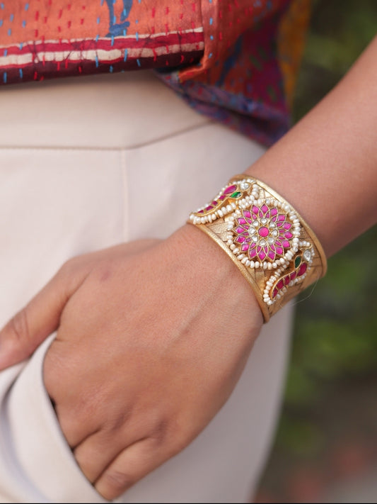 Woman wearing Naksa’s Sunkissed Rose Cuff in gold-finished silver, featuring a pink stoneflower with pearl.