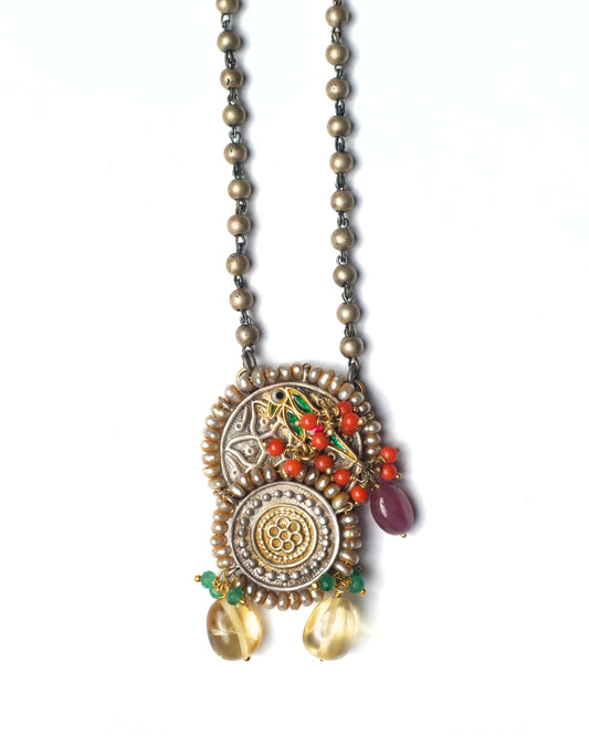 Close-up of Rustwing Coin Necklace highlighting dual-tone coin textures, bird detailing, and orange stone accents